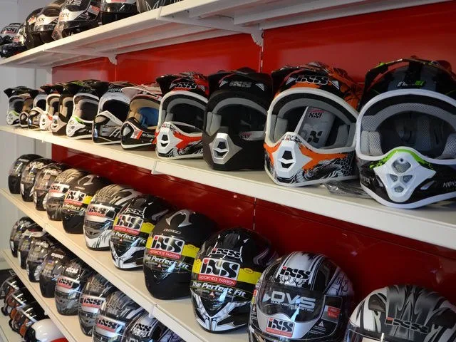 Helmregal mit Motocross- und Straßenhelmen in mehreren Reihen