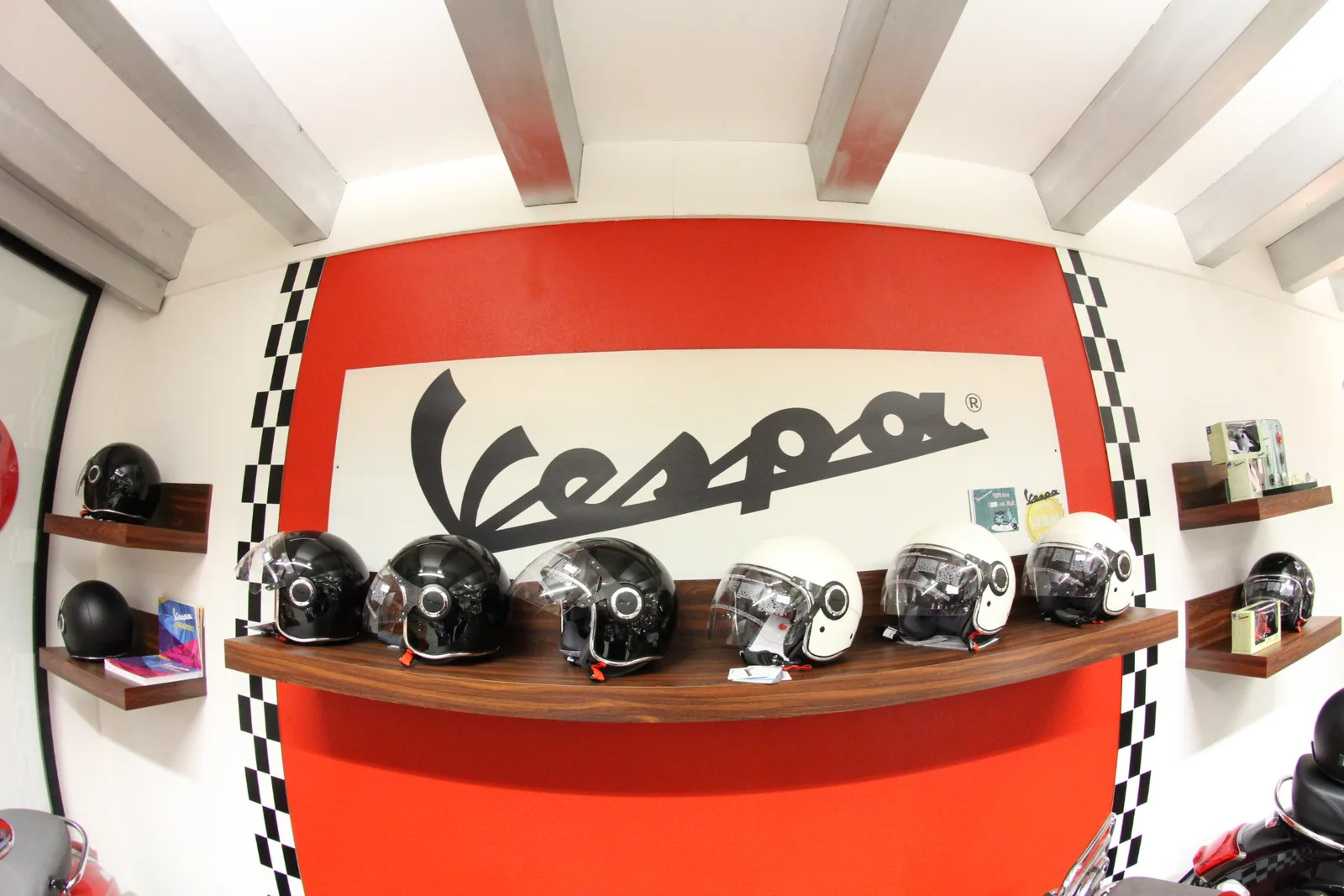 Rote Vespa-Wand mit Helmen auf einem Holzbord